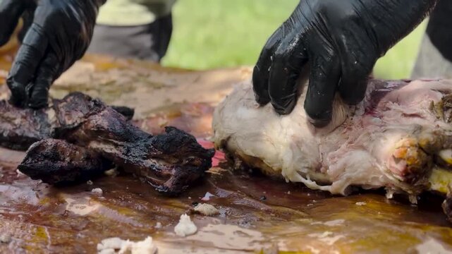 Close-up video footage of a chef wearing black gloves using a sharp knife to slice freshly smoked barbecue meat on butcher paper.
