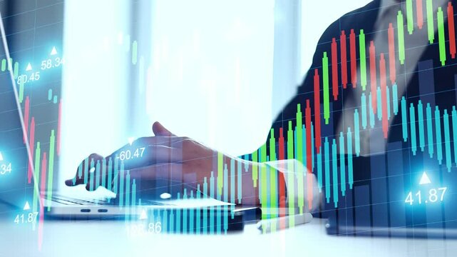 A person is using a laptop to review stock market performance. Colorful charts display data trends. It is likely daytime and suggests work in a business office.