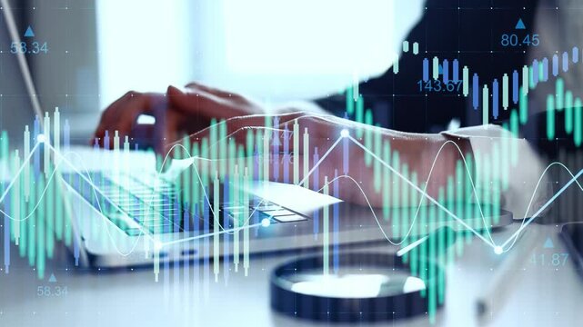 A person is typing on a laptop in a workspace. Graphs and data are displayed on the screen. The scene shows a focus on trading and market analysis activity.