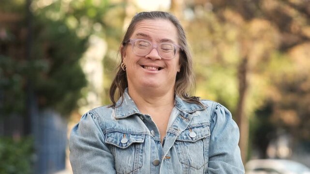 Portrait of a joyful middle aged woman with Down syndrome laughing and looking at the camera. Authentic shot capturing happiness and inclusion