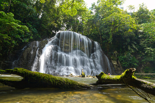 Wapsdori Waterfall cascades smoothly over multi-tiered limestone rocks surrounded by a dense tropical rainforest in Biak Papua Indonesia.