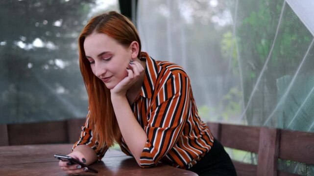 Young Woman Using Smartphone Outdoors at Table