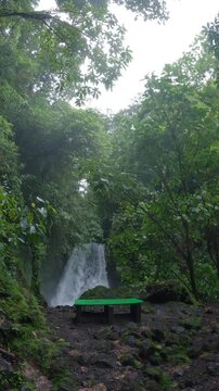 Revealing view of a stunning cascade in the Arenal Volcano National Park. The trail leads through a dense, tropical rainforest