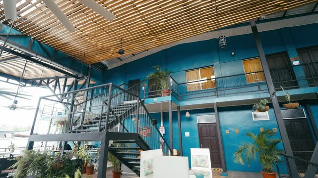 Colorful interior courtyard of a modern hostel in Costa Rica. Industrial style architecture with metal stairs, balconies, and plants