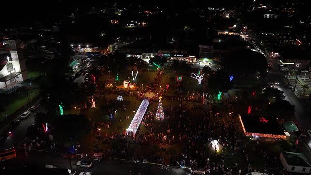Nighttime aerial view of a crowded public park in La Fortuna, Costa Rica. People celebrating Christmas with festive lights and decorations