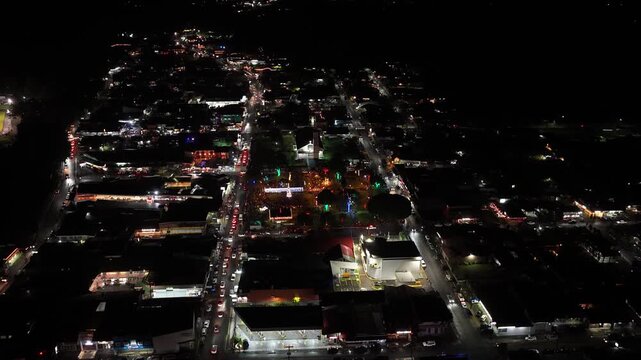Aerial view flying over the illuminated town of La Fortuna in Costa Rica at night. City lights illuminating the streets and buildings