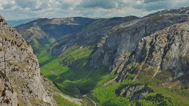 Aerial view of amazing rocky mountains in snow and green valley, Prokletie park, Montenegro and Albania, 4k