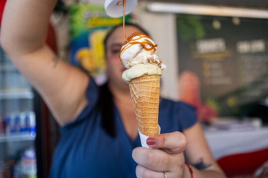 Woman pouring caramel sauce on ice cream cone