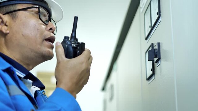 Electrical technician checking UPS backup power performance using a control screen installed on an electrical cabinet for preventive maintenance and safety.