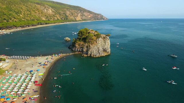 Aerial drone rotation around Scoglio Mingardo sea rock at sunset in Palinuro Cilento Italy. Twin coves with boats on Marinella beach 4K
