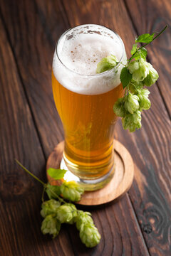 Freshly Brewed Golden Beer with Hops on Rustic Wooden Table Background