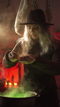 witch stands in her home, surrounded by cobwebs and bundles of dried herbs, preparing a poison or a love potion she chants a spell and tosses dried herbs into a cauldron of bubbling green liquid.