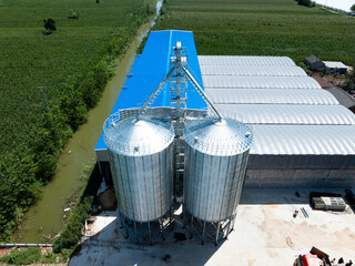 large metal grain silos storage facility next to green farmland fields © zhu difeng