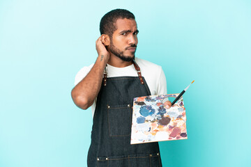 Young artist latin man holding a palette isolated on blue background having doubts © luismolinero