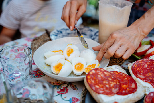 Close up of woman preparing soft boiled eggs for Mediterranean family breakfast outdoors