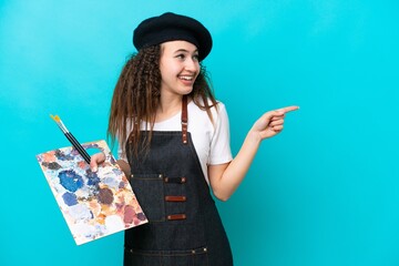 Young artist Arab woman holding a palette isolated on blue background pointing finger to the side and presenting a product © luismolinero