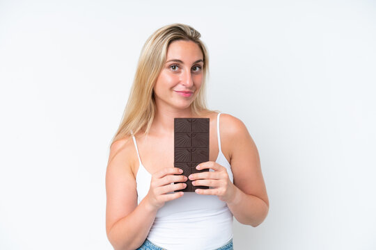 Young caucasian woman isolated on white background taking a chocolate tablet and happy