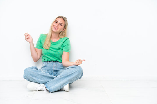 Young caucasian woman sitting on the floor isolated on white background making guitar gesture