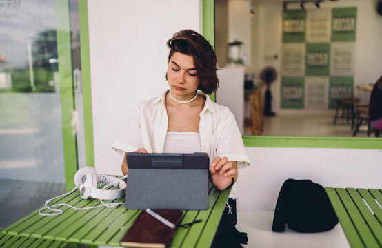 Hybrid lifestyle smart tech integration lets Caucasian female freelancer engage in online learning on tablet at cozy workspace, achieving digital wellbeing and flexible workflow autonomy