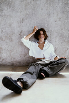 Cozy productivity flexible workflow choice allows happy Caucasian female student laugh joyfully while resting against rustic concrete wall, practicing modern self-employment choices