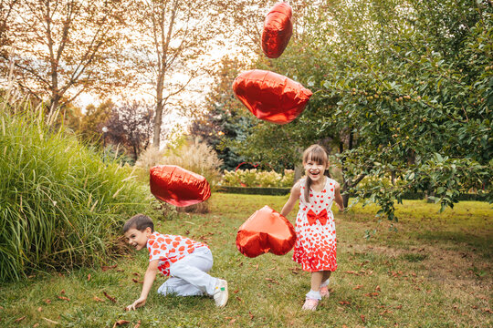 Children Play in a Garden During Summer While Having Fun With Heart-Shaped Balloons on Valentine's Day
