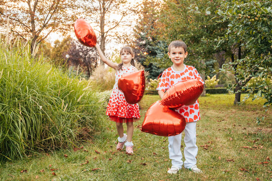 Two Children Celebrate Summer With Heart-Shaped Balloons During a Holiday in the Garden on Valentine's Day