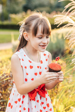 Children Enjoy a Summer Holiday as a Girl Holds a Red Cupcake With a Heart Decoration While Smiling in a Garden