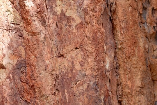 Close up of rough weathered red rock texture showing cracks and natural stone surface details
