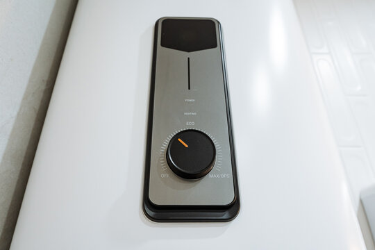 Closeup of wall mounted water heater control panel showing rotary dial set to low power and eco mode