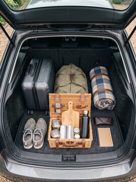 Open car trunk neatly packed with backpack, shoes, boxes and outdoor travel gear, road trip preparation, organized packing, adventure travel, weekend getaway.