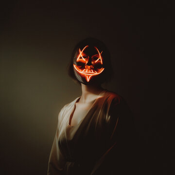 Woman wearing illuminated mask standing in darkroom 
