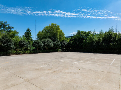empty concrete parking lot ground with green trees and blue sky background