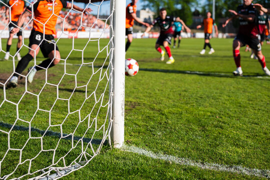 Action on the Soccer Pitch With Players in Motion Seen Through a Stadium Goal Net and Focusing on the goalpost.