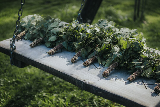 Bundles of fresh green herbs arranged neatly on a wooden swing in a grassy outdoor setting, showcasing natural textures and vibrant colors