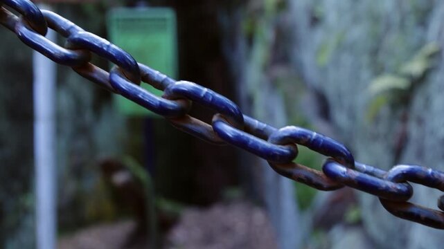 Close Up of Metal Chain Rack Focus to Mining Warning Sign in Rock Gorge