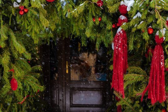 Festive Christmas evergreen branches adorned with red ornaments and ribbons in snowfall