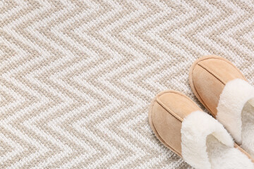 Comfort and relaxation at home, pair of soft beige slippers on a textured rug with copy space for cozy lifestyle and leisure time interior design © Pixel-Shot
