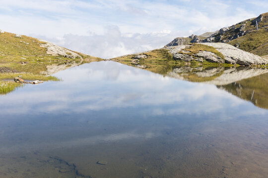 Le lac des Moutons aux Arcs, en Savoie : un lac d'altitude dans les Alpes fran&ccedil;aises, entour&eacute; de montagnes rocheuses et de vaches. Reflets des montagnes &mdash; dont le mont Blanc &mdash; dans les eaux du lac.