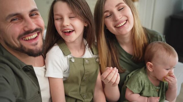 Happy family talk on video call with friends family. Mother father two children daughters talking speaking online at home. Family mom dad parents baby girls kids smiling laughing webcamera view