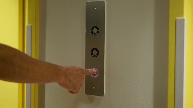 Hand presses illuminated elevator button, signaling a journey begins