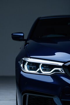 Front quarter luxury sedan headlight with triple led rings in dark blue for automotive background and banner design emphasizing illuminated lenses