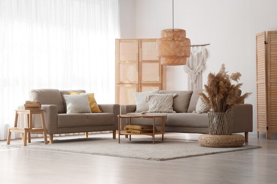 Interior of light living room with grey sofas, wooden table and folding screens