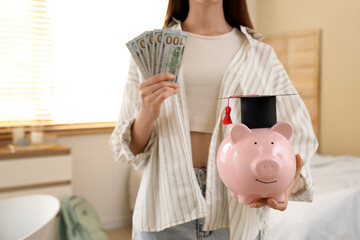 Female student with money and piggy bank at home, closeup. Education savings concept