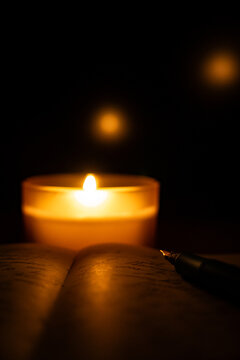 Small candle beside notebook in a dark room