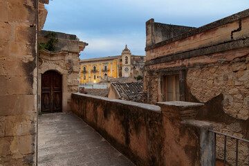 Fototapeta premium Ancient stone city street with historic buildings and a distant church tower