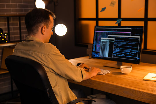 Male programmer working with computer in office at night