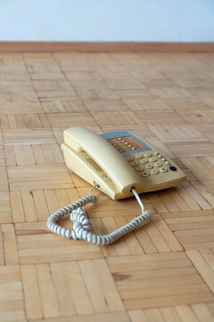 Old apartment interior with outdated landline telephone on worn parquet floor, neglected residential space requiring renovation and home refurbishment