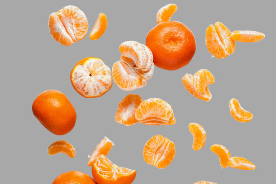 Flying sweet ripe mandarins on grey background