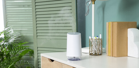 Obraz premium Wellness and air quality, modern ultrasonic humidifier diffusing mist on a home office desk for relaxation and healthy indoor environment