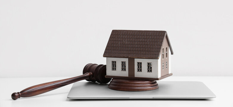 Real estate law and property litigation, wooden judge gavel with house model on laptop for legal advice and housing dispute resolution in office
